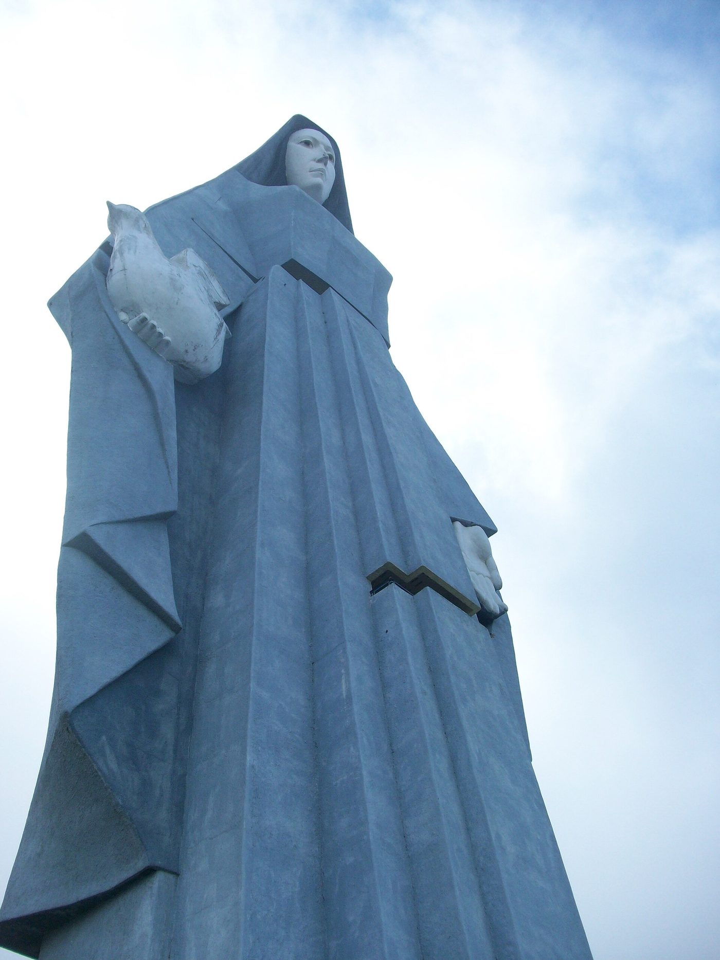 El Monumento a la Virgen de la Paz, en Trujillo, visto desde abajo con la paloma en la mano y el cielo detrás